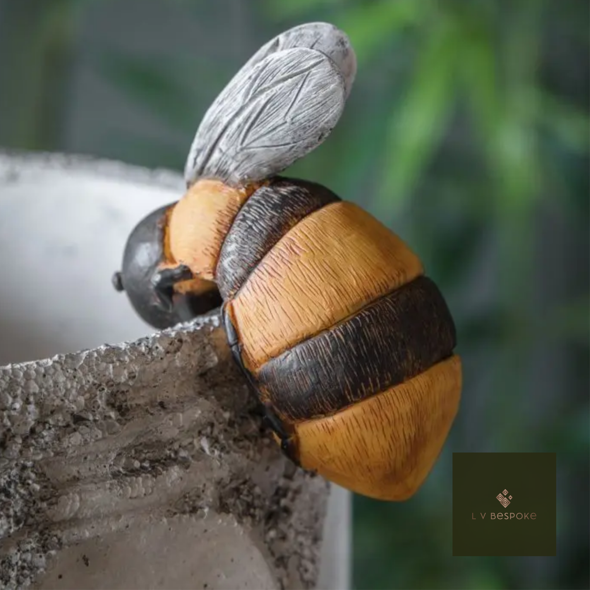 Bee sculpture on a concrete surface with a blurred green background