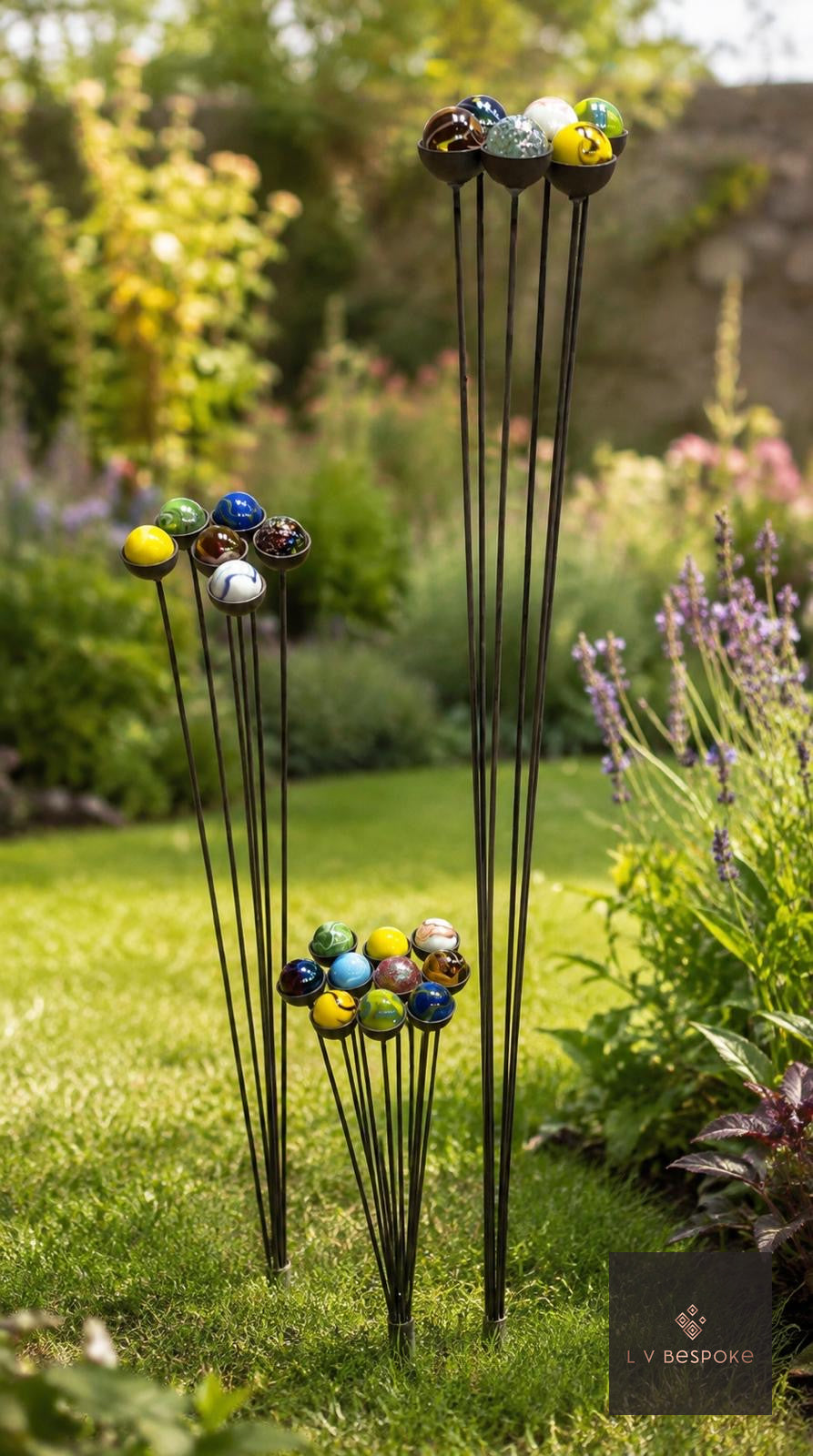 Raw steel short and tall clusters of five garden stakes with amber glass marbles, planted in a border