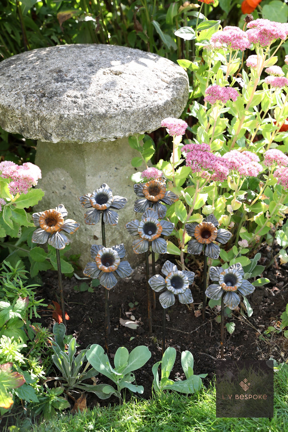 Raw steel Daffodil flower head on a garden stake, planted in a border