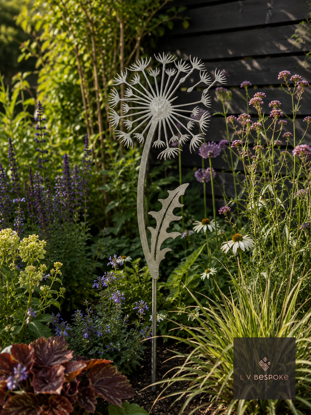 Raw steel Dandelion flower head on a garden stake, planted in a border