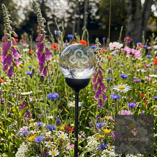 Glowing glass sphere on a stand in a field of colorful flowers.